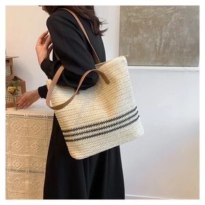 Detail showing woven texture and brown leather straps of the summer straw tote bag