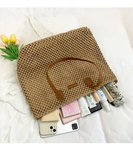 Close-up of straw tote bag with brown leather handles showing spacious inner storage