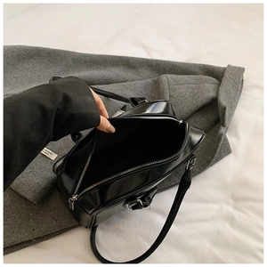 Detail shot of the glossy black patent leather material and sleek silver zipper closure
