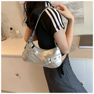 Detail of silver metallic underarm bag with decorative eyelet straps and Y2K aesthetic