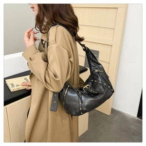 Détail d'un sac hobo punk noir avec clous dorés et fermetures éclair métalliques