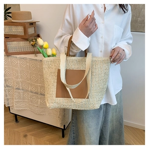 Close-up of beige straw tote with brown leather patch and dual strap details