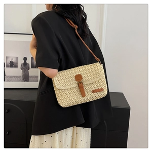 Detail of cream straw crossbody bag with brown leather strap and buckle for summer
