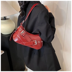 Macro shot of a red patent leather shoulder bag with metallic eyelets and strap detail