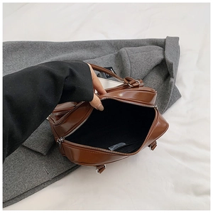 Macro view of the brown glossy handbag interior showing black lining and zip pocket