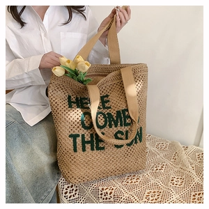 Straw woven tote bag detail featuring Here Comes The Sun print and sturdy handles