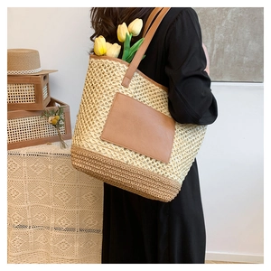 Detail of hand-woven straw tote with brown leather pocket and long shoulder straps