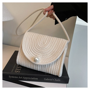 Detailed view of woven cotton rope texture and white faux pearl closure on beach bag