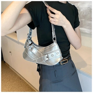 Detail view of metallic silver crescent underarm bag featuring decorative buckles and eyelets