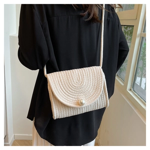 Detail of hand-woven straw bag featuring a large pearl clasp and concentric circle texture