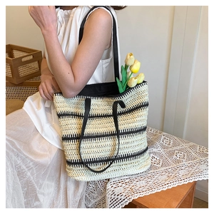 Detailed macro view of large black and white striped woven straw tote bag with long handles