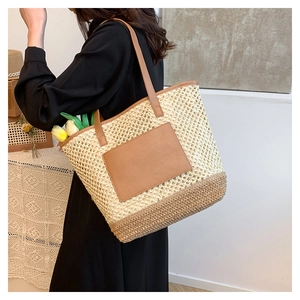 Detail of hand-woven straw tote bag showing beige mesh texture and brown leather patch