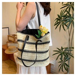 Detail of hand-woven straw tote with black stripes and black faux leather handles
