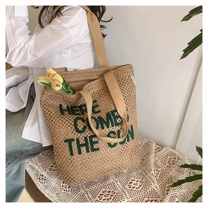 Detail of woven beach tote featuring HERE COMES THE SUN print and durable ribbon handles