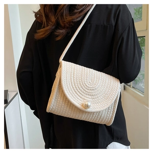 Detailed view of handmade woven straw bag with pearl closure and braided cotton texture