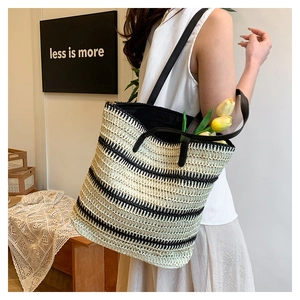 Detail shot of woven straw tote bag with black stripes and long shoulder straps