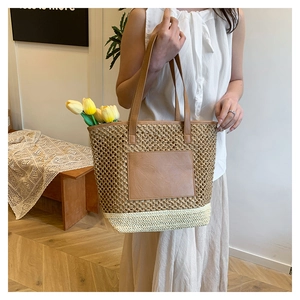 Detail of hand-woven straw tote bag featuring a brown leather pocket and tulip accent