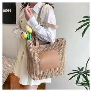 Detail of hand-woven straw tote bag showing brown leather patch and woven texture