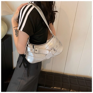 Detail of silver metallic Y2K shoulder bag with decorative eyelet belts on a female model
