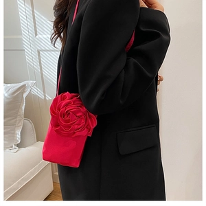Détail d'une grande rose en satin rouge 3D sur un sac porté avec un costume noir