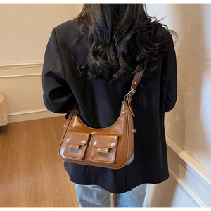 Brown faux leather shoulder bag featuring silver rivets and double pockets on a model