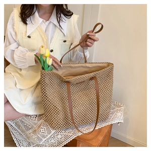 Detail of hand-woven straw tote bag featuring intricate mesh texture and leather straps