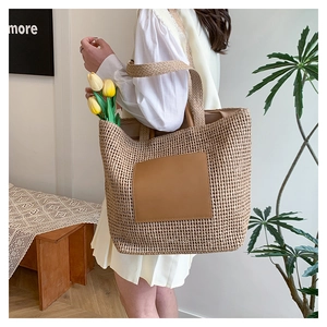 Detail of summer straw tote bag featuring leather patch and woven handles with tulips