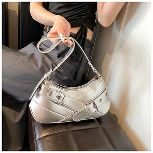 Close-up of metallic silver underarm bag with buckle straps and eyelet details
