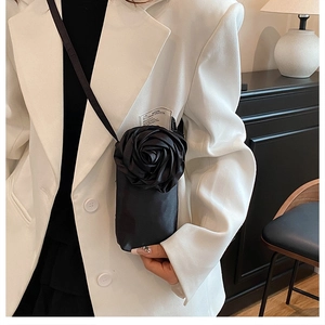 Sac bandoulière pour téléphone avec rose satinée 3D porté sur un blazer blanc chic