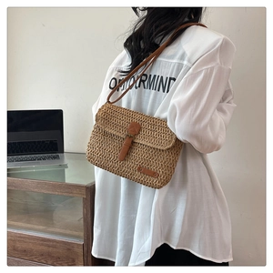 Detail of the woven straw shoulder bag with leather strap and metal buckle closure