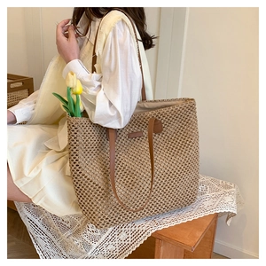 Detail view of woven straw tote bag with brown leather handles on lace background
