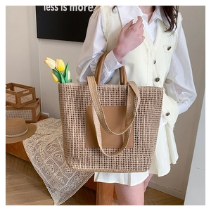 Detailed macro view of large woven straw tote bag with brown leather handles and side pocket