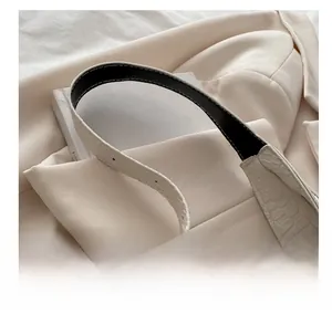 Detailaufnahme der cremefarbenen Tasche mit Krokoprägung und verstellbarer Metallschnalle