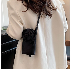 Détail d'une grande rose 3D noire en soie sur la bandoulière d'un sac de téléphone