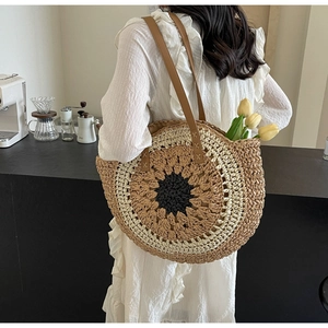 Detailed macro view of woven straw shoulder bag featuring sunflower pattern and leather straps