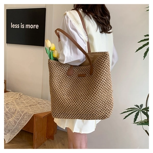 Detailed texture of hand-woven straw tote bag with brown leather shoulder strap