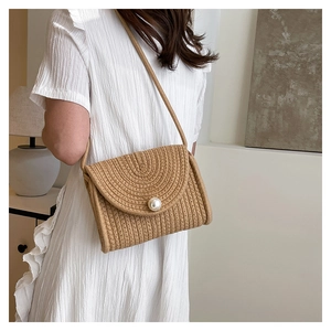 Detail view of woven straw bag featuring a large pearl button and spiral texture design