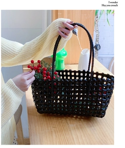 Close-up of black hollow woven tote bag featuring glossy texture and red berry decoration