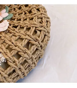 Detail of woven straw bag featuring handmade 3D pink fabric flowers and green leaves