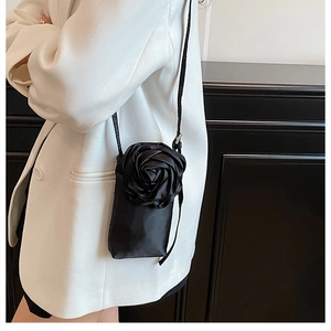 Détail de l'élégante rose 3D en satin noir sur un sac à bandoulière avec sangle