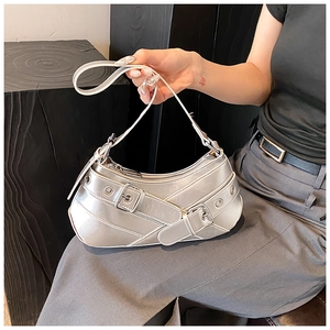 Detail of silver metallic crescent bag featuring buckled straps and metal eyelets