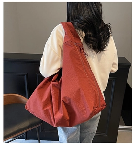 Dettaglio della borsa a tracolla in nylon rosso mattone che mostra materiale e dimensioni