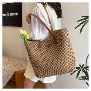 Detail of hand-woven straw tote bag with brown leather straps and large capacity for summer