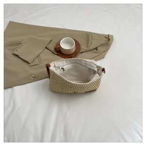 Close-up of beige woven straw bag with zipper closure and white inner lining details