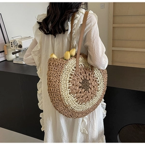 Detail of round straw tote bag with sunflower weave pattern and leather straps