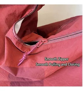 Dettaglio della cerniera in nylon e cordino intrecciato sulla borsa rossa