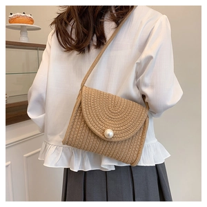 Detail of straw crossbody bag with circular spiral texture and large pearl button