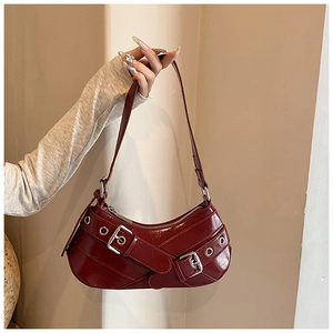 Close-up of burgundy crescent bag with silver buckles and polished leather texture