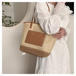 Detail of hand-woven straw tote bag with brown leather pocket and slim shoulder strap