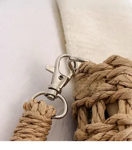 Close-up of the shiny silver metal lobster clasp and thick woven rope strap on straw bag